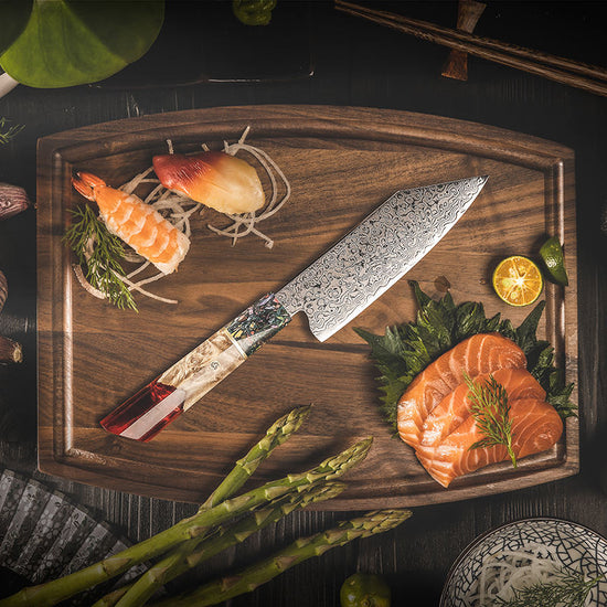 The Damara Hirameki Bunka knife displayed on a wooden board next to salmon sashimi, sushi, and asparagus.