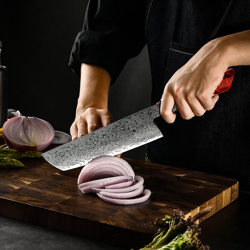 A chef’s hands using the Damara Ryujin Kiritsuke knife to slice a red onion on a wooden cutting board.