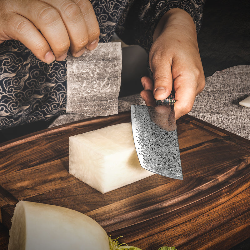 A chef uses the Damara Mizu Nakiri knife to slice a daikon radish into a paper-thin sheet, demonstrating its sharpness.