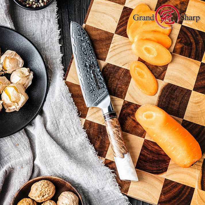 Top-down view of the Damara Chisai paring knife on a checkered cutting board next to a sliced carrot and walnuts.